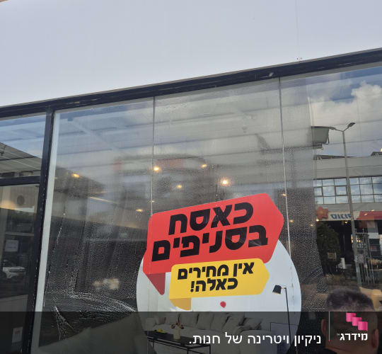 ניקוי חלון עם שלט פרסומי על מבצע